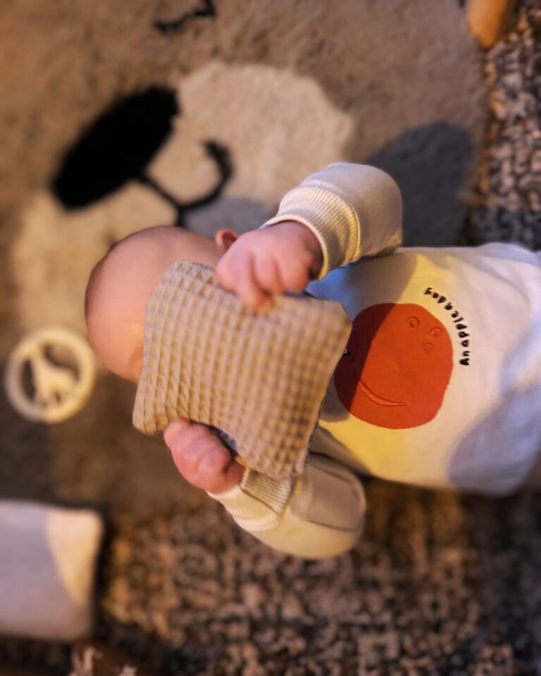 baby die speelt met een pittenzakje en dit voor zijn gezichtje houd
